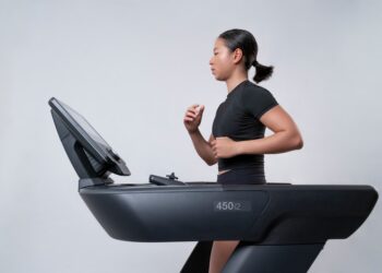 A woman focused on her indoor training session on a treadmill inside a modern Dubai gym, preparing for an autumn race
