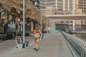 A woman stretching on a shaded outdoor path as part of her morning routine in Dubai's early hours