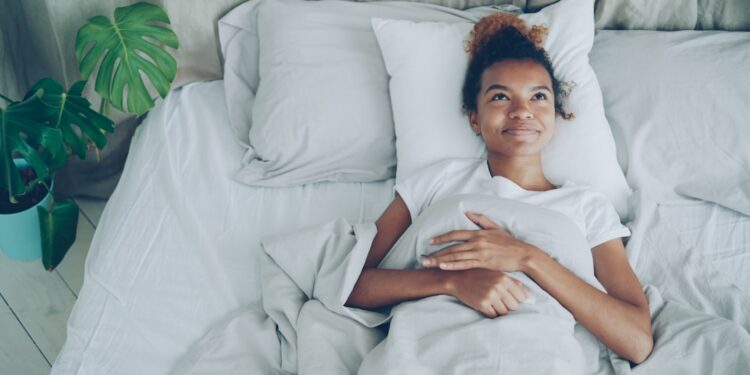A woman opening curtains to morning sunlight as part of her sleep schedule reset in Dubai