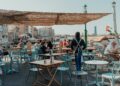 women-friends-laughing-outdoor-dubai-cafe-unsplash - DUBAIwebzine Two women enjoying coffee at an outdoor cafe as part of their social life in Dubai after summer