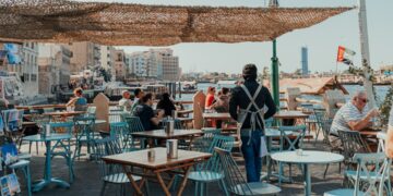 women-friends-laughing-outdoor-dubai-cafe-unsplash - DUBAIwebzine Two women enjoying coffee at an outdoor cafe as part of their social life in Dubai after summer