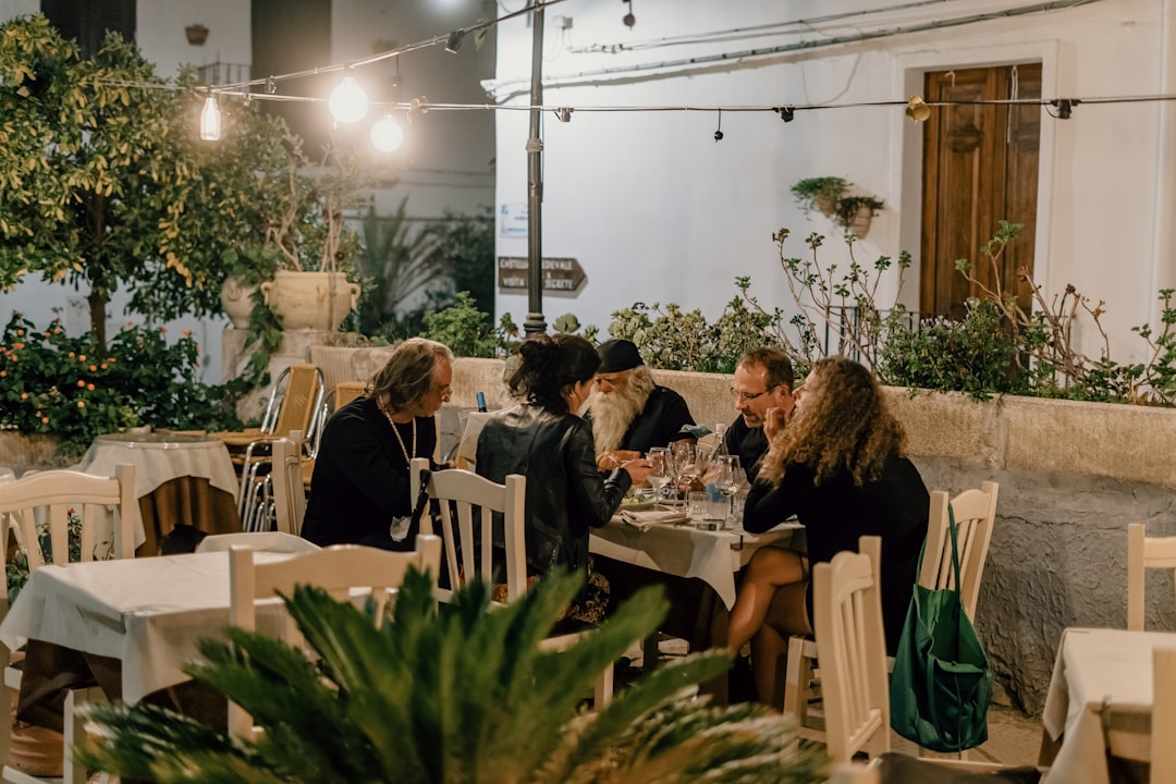 Een groep vrienden die gerechten deelt aan een tafel buiten en de vreugde van terrasdineren in Dubai vastlegt