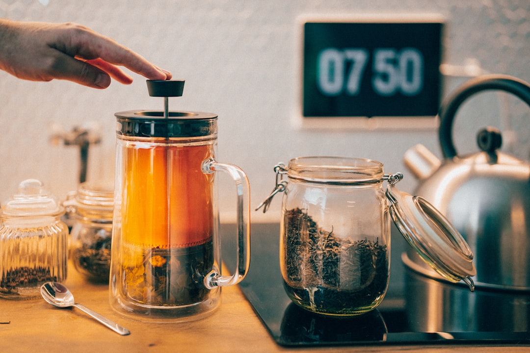 A person filling a glass jar with bulk goods in a modern kitchen, part of a plastic use reduction routine at home