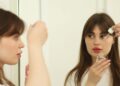 A woman applying rich moisturiser in a bright bathroom as part of her Dubai skincare routine for autumn