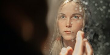A woman applying a rich moisturizer as part of her updated skincare regimen during Dubai's seasonal humidity drop