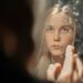 A woman applying a rich moisturizer as part of her updated skincare regimen during Dubai's seasonal humidity drop