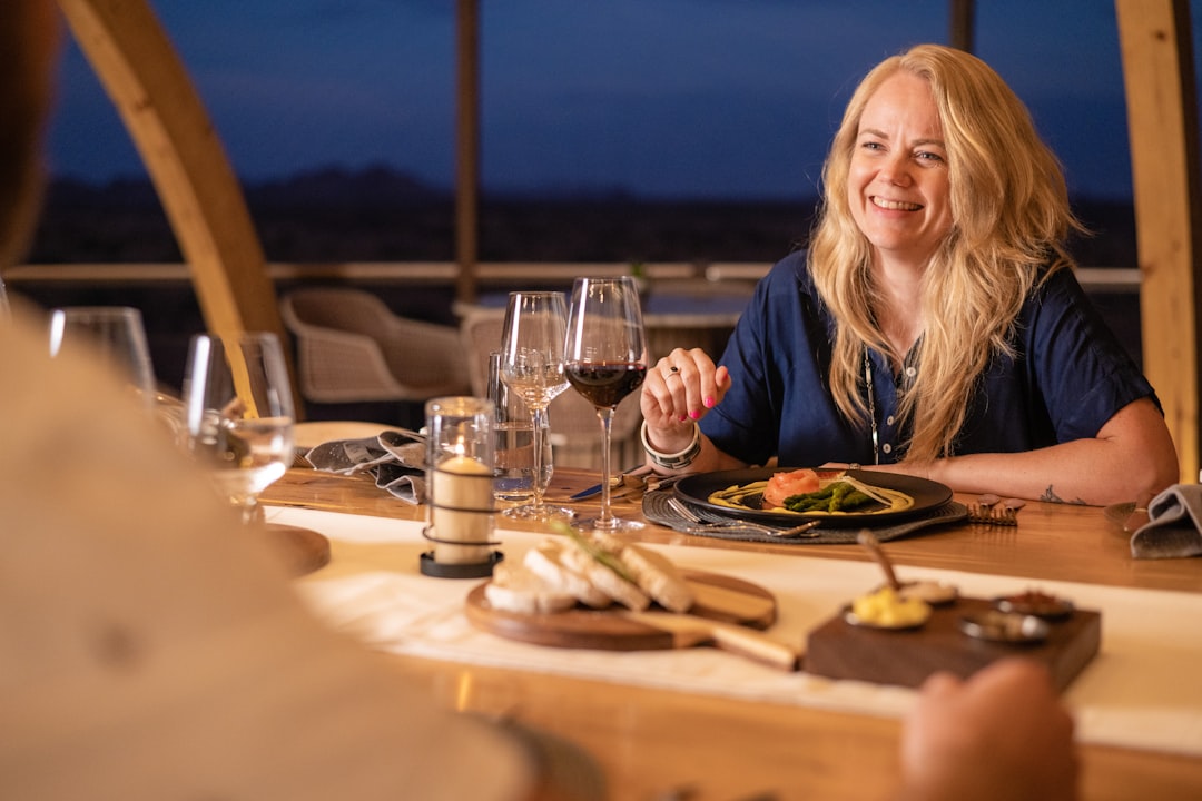 Een vrouw zittend aan een tafel buiten onder een sterrenhemel in de woestijn, terwijl ze geniet van terrasdineren in Dubai buiten de stad