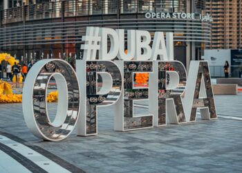 A visitor studying the Dubai cultural calendar programme outside Dubai Opera before an evening performance