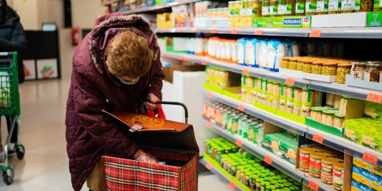 A woman choosing loose produce at a Dubai supermarket, reducing plastic use with a reusable mesh shopping bag