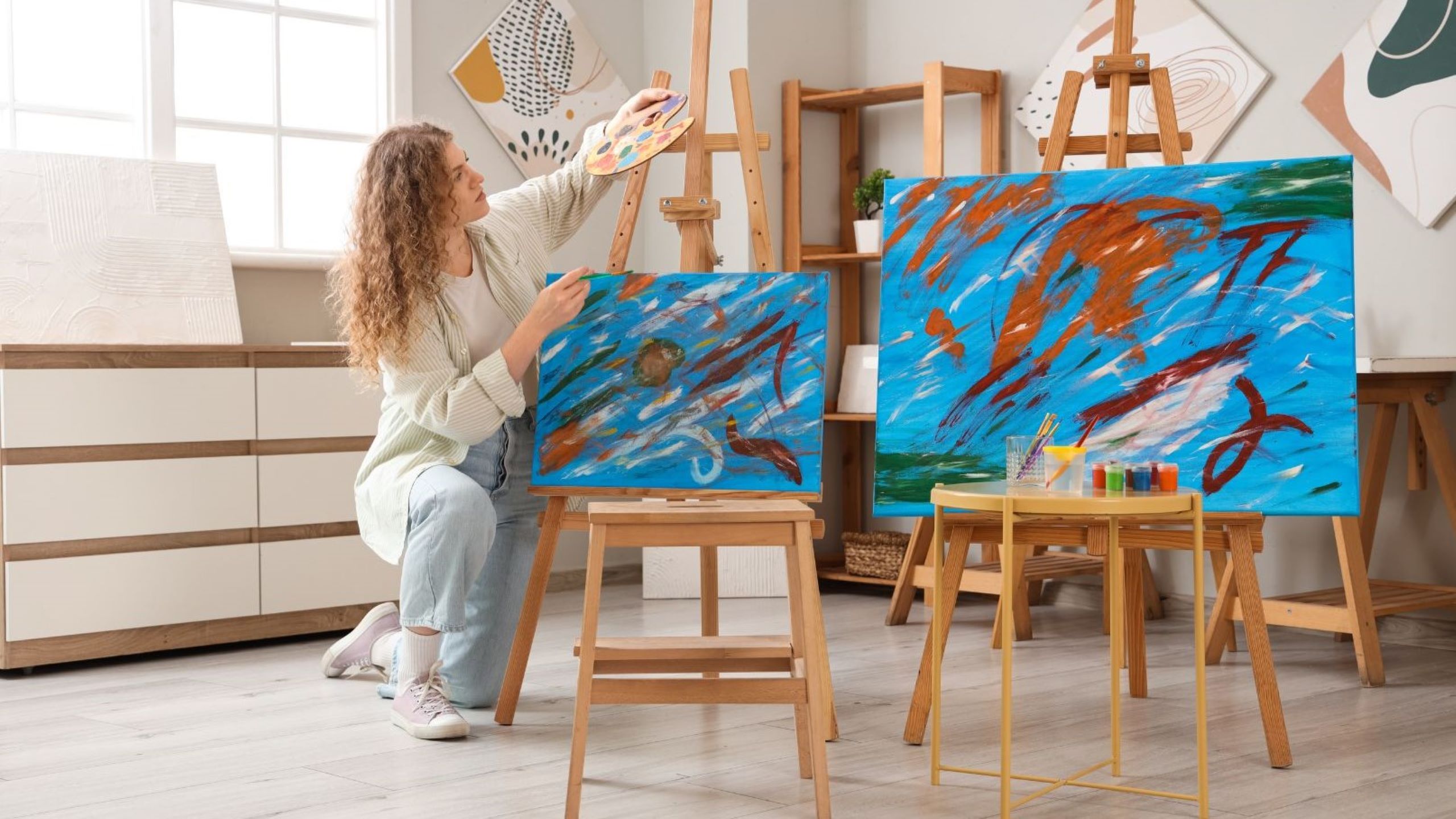Artista pintando sobre un lienzo en un estudio de arte luminoso en Dubái talleres de arte clases en estudio creativo pintura