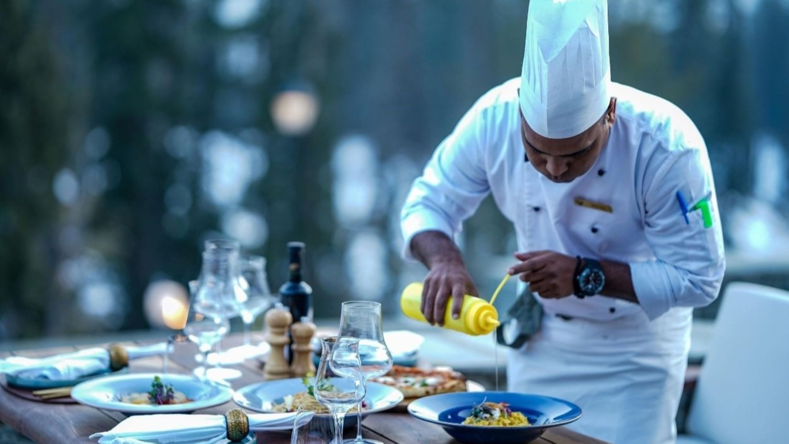 Renombrado chef de celebridades emplatando un exquisito plato de alta cocina en un restaurante con estrellas Michelin en Dubái, representando a las leyendas culinarias que crean cocina de autor para experiencias gastronómicas de clase mundial
