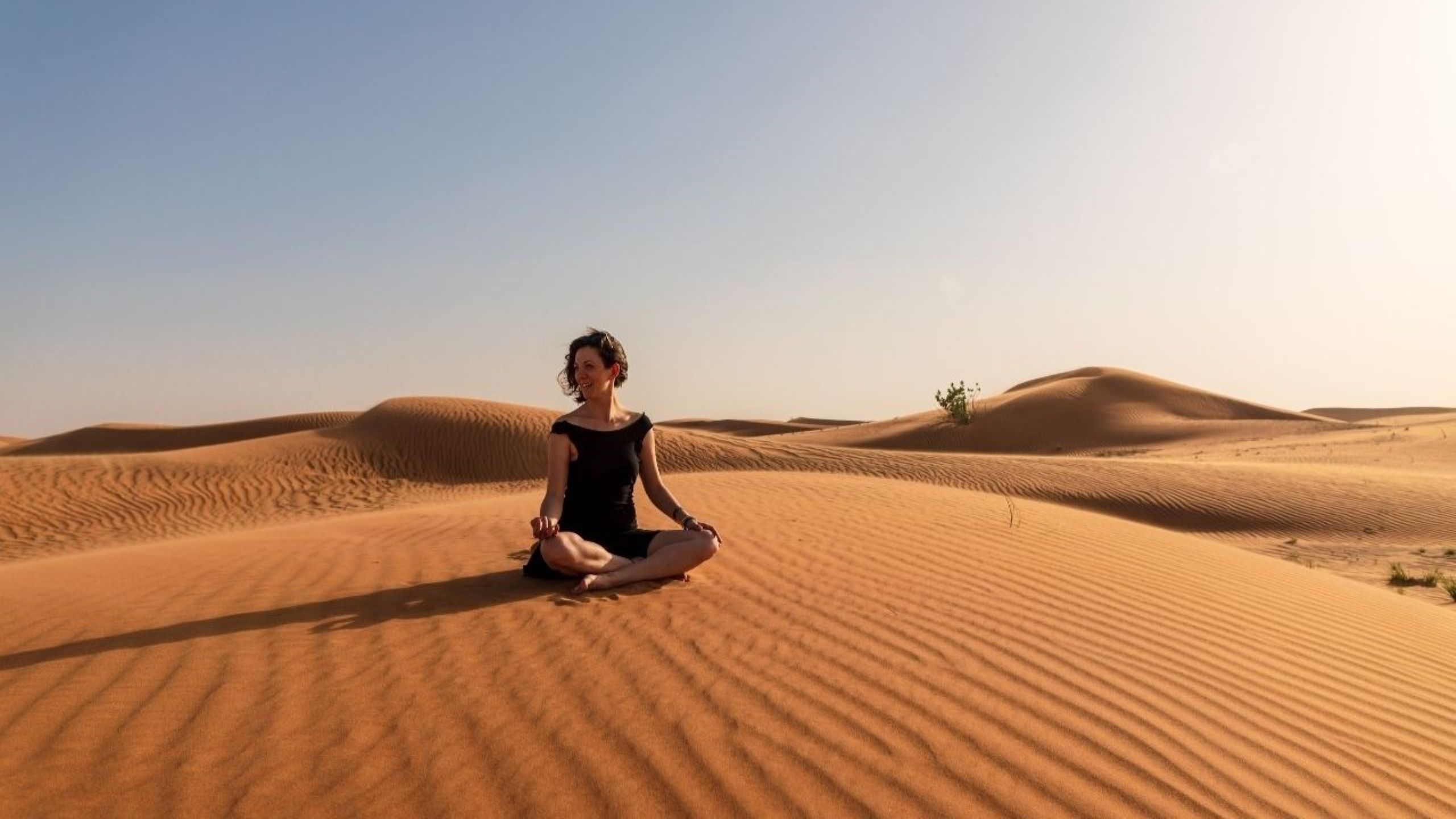 Sesión pacífica de meditación y yoga en el desierto en destinos de desintoxicación digital de Dubái como Al Maha Resort, representando retiros de bienestar sin pantallas centrados en la atención plena, la inmersión en la naturaleza y la claridad mental