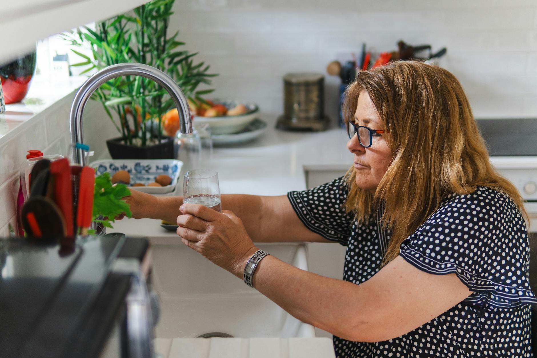 Una donna che ispeziona un rubinetto della cucina in una moderna casa di Dubai per ridurre l'uso domestico dell'acqua