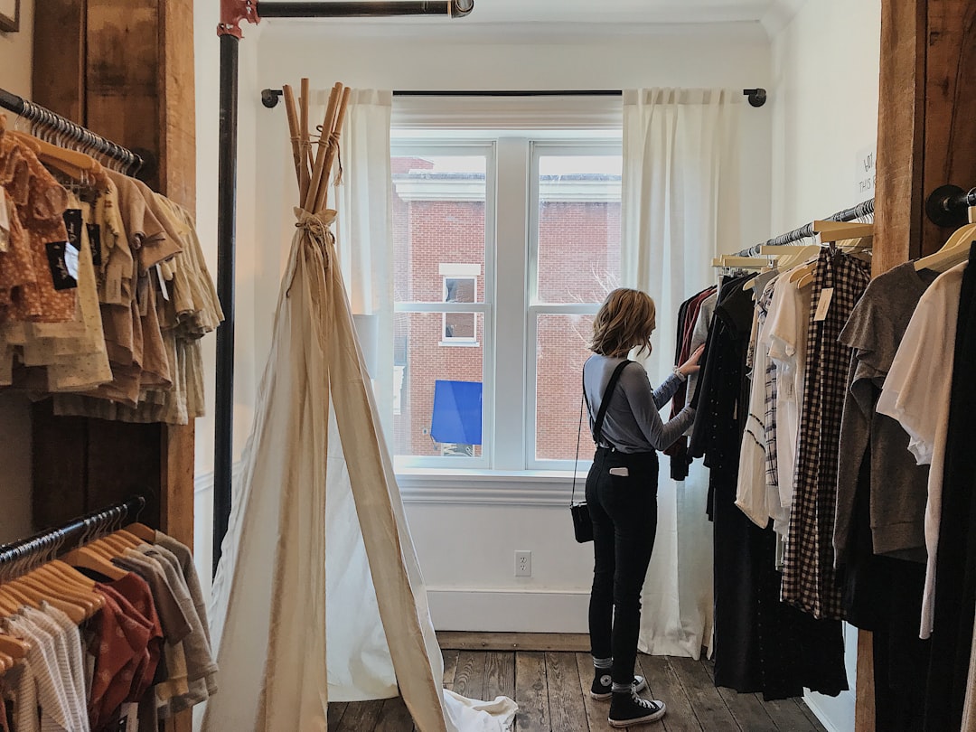 Una donna sfoglia capi di moda lenta in una boutique etica a Dubai, esaminando con cura la qualità del tessuto.