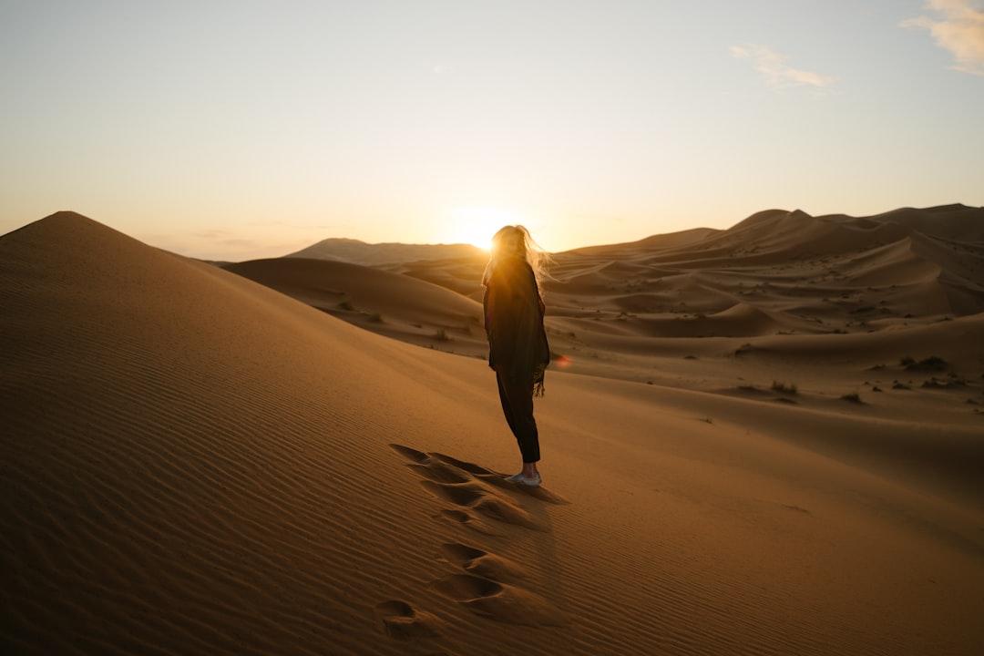 Um viajante assistindo ao nascer do sol sobre as dunas douradas durante uma escapada de verão no deserto perto de Dubai