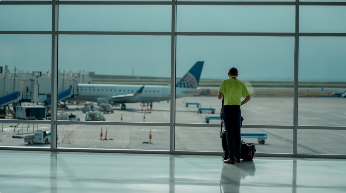 Un voyageur consultant le tableau des départs à l'aéroport international de Dubaï avant de choisir des vols d'été vers l'Europe