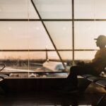 Un voyageur à l'aéroport international de Dubaï vérifiant les tarifs long-courrier sur un smartphone avant de réserver un vol d'été