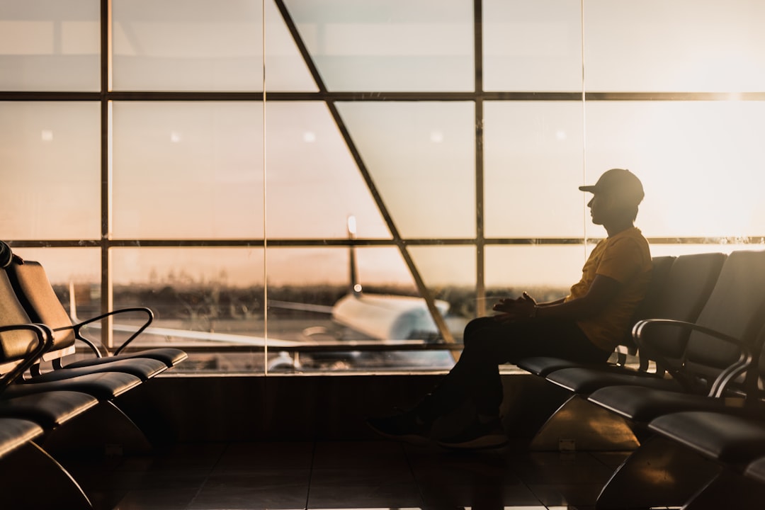 Un voyageur à l'aéroport international de Dubaï vérifiant les tarifs long-courrier sur un smartphone avant de réserver un vol d'été