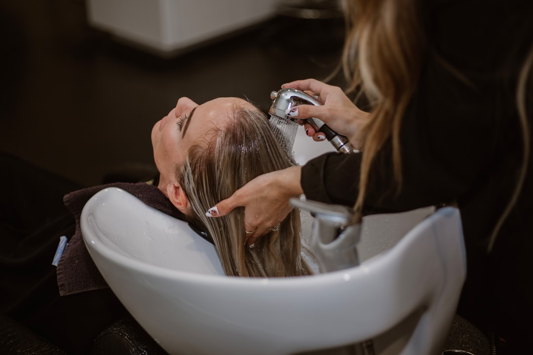Une coiffeuse appliquant des soins capillaires professionnels sur les cheveux d'une cliente dans un salon de Dubaï, protégeant contre l'humidité et les frisottis.