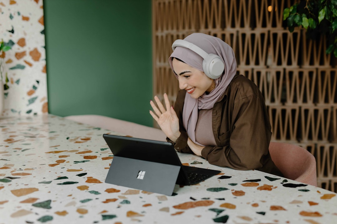 Une nomade numérique travaillant dans un espace de coworking lumineux à Dubaï, avec un ordinateur portable ouvert et la vue sur la ville en arrière-plan