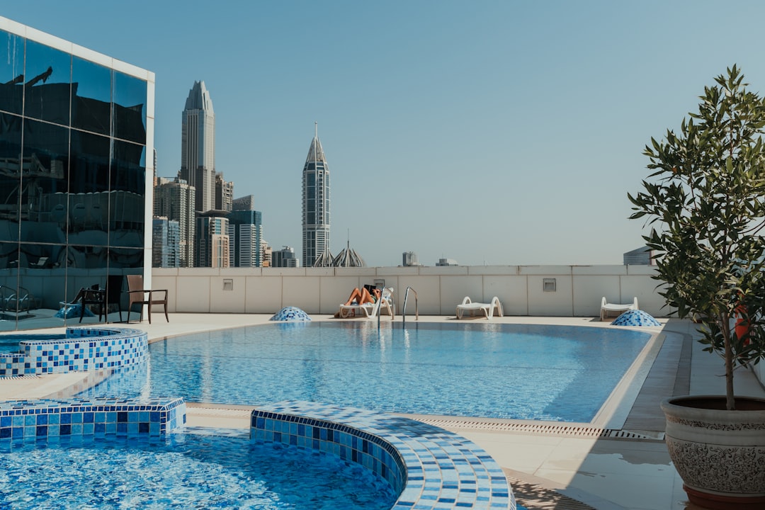 Una donna si rilassa ai bordi di una delle piscine di lusso più sbalorditive di Dubai con lo skyline della città dietro di lei