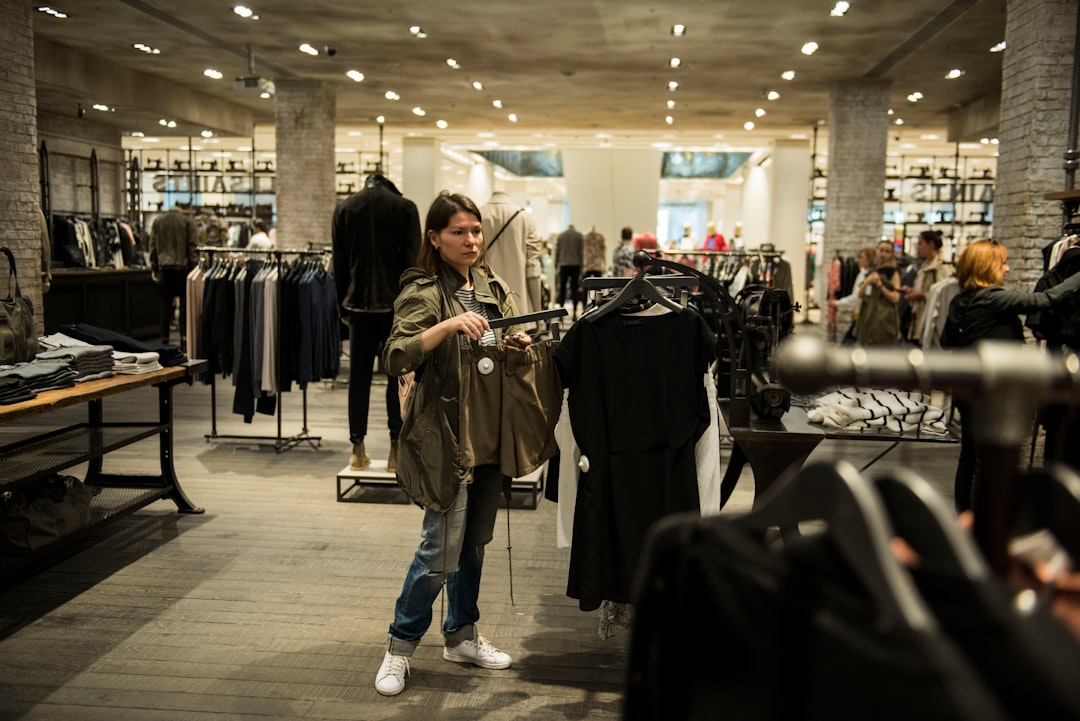 Une femme parcourant les portants de vêtements dans une boutique de seconde main, constituant une garde-robe durable à Dubaï avec un budget intermédiaire.
