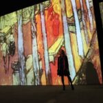 Une femme traverse une salle de projection numérique lumineuse lors d'une expérience d'art immersif dans un centre commercial de Dubaï