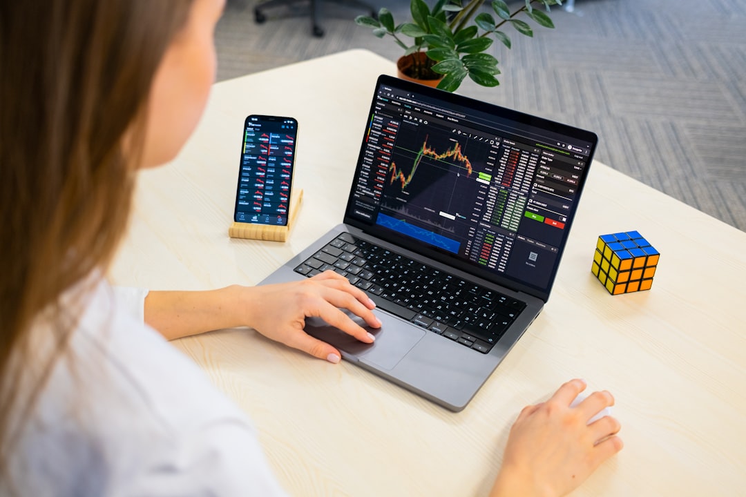 Une femme professionnelle examinant les données de dividendes sur un ordinateur portable dans le cadre de ses recherches d'investissement en FPI de Dubaï