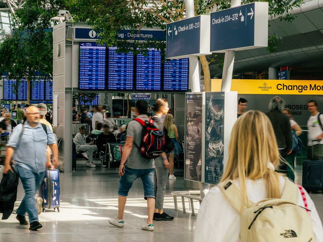 Una viajera sonriente revisa su tarjeta de embarque en una puerta de salida de un centro de tránsito de Dubái, preparándose para su vuelo de conexión.