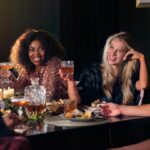 Une femme profitant d'un repas élégant dans un club de dining réservé aux membres à Dubaï, entourée d'intérieurs raffinés et d'un éclairage subtil.