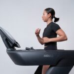 Une femme concentrée sur sa séance d'entraînement en salle sur un tapis roulant dans une salle de sport moderne de Dubaï, se préparant pour une course d'automne