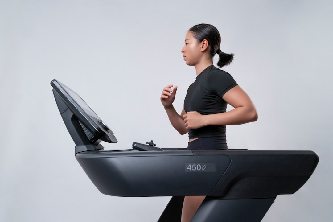 Uma mulher focada em sua sessão de treinamento interno em uma esteira dentro de uma academia moderna em Dubai, preparando-se para uma corrida de outono