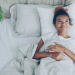 Une femme ouvrant les rideaux à la lumière du matin dans le cadre de sa réinitialisation du cycle de sommeil à Dubaï