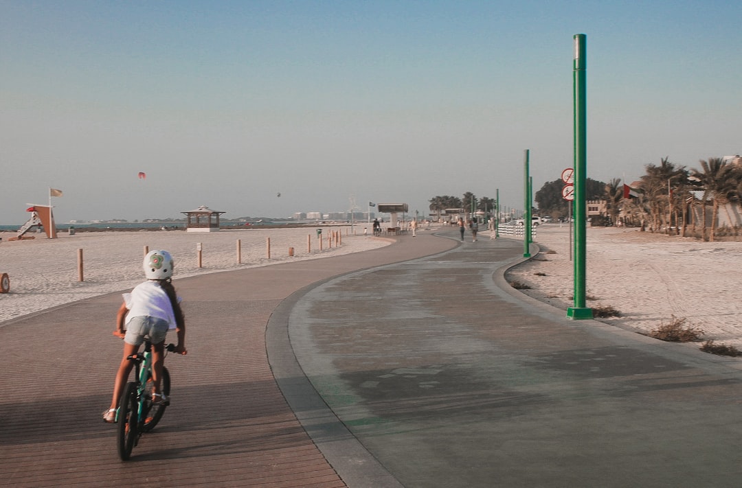 Une famille fait du vélo le long d'une piste en bord de mer à Dubaï, profitant ensemble des activités de plein air sous la lumière du petit matin
